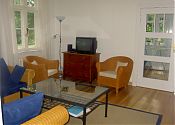Wohnzimmer mit Tisch, Korbsesseln und Fernseher